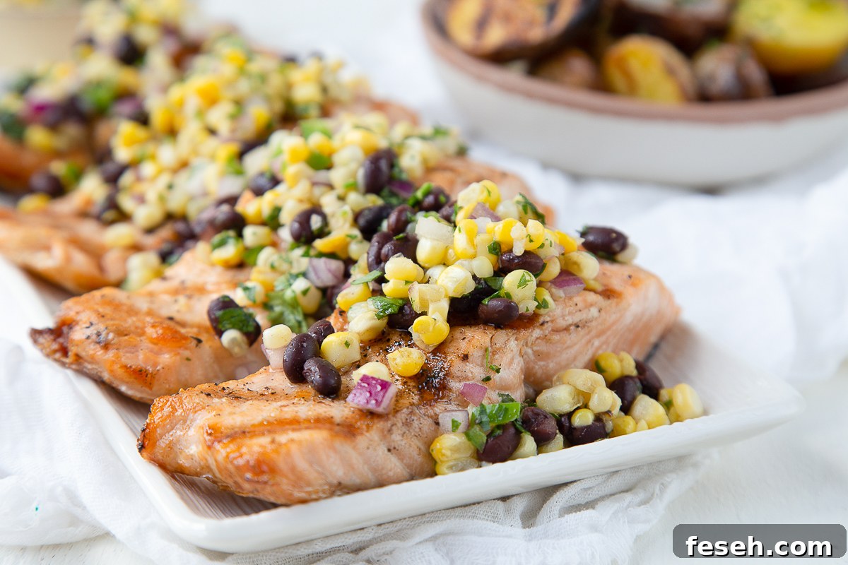 grilled salmon topped with corn salsa on a white platter