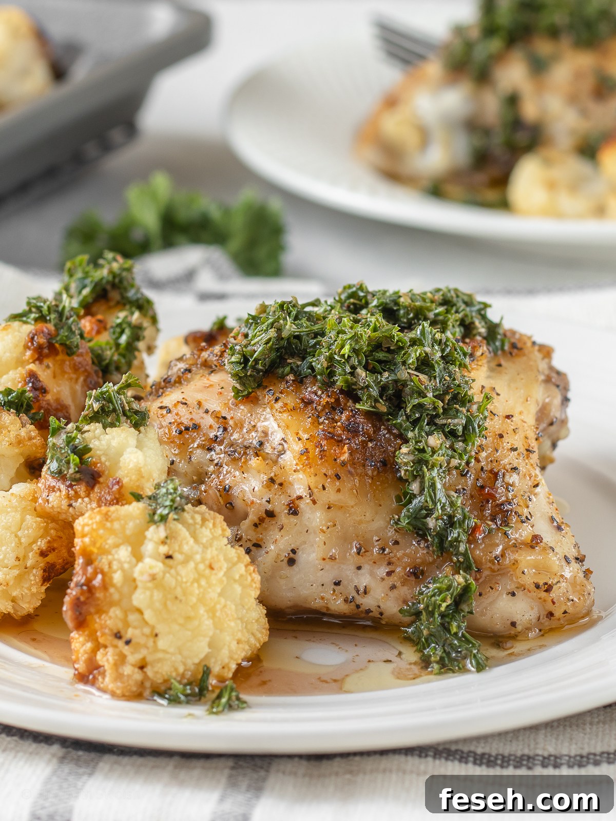 A plate of baked cajun chicken thighs and roasted cauliflower ready to eat.