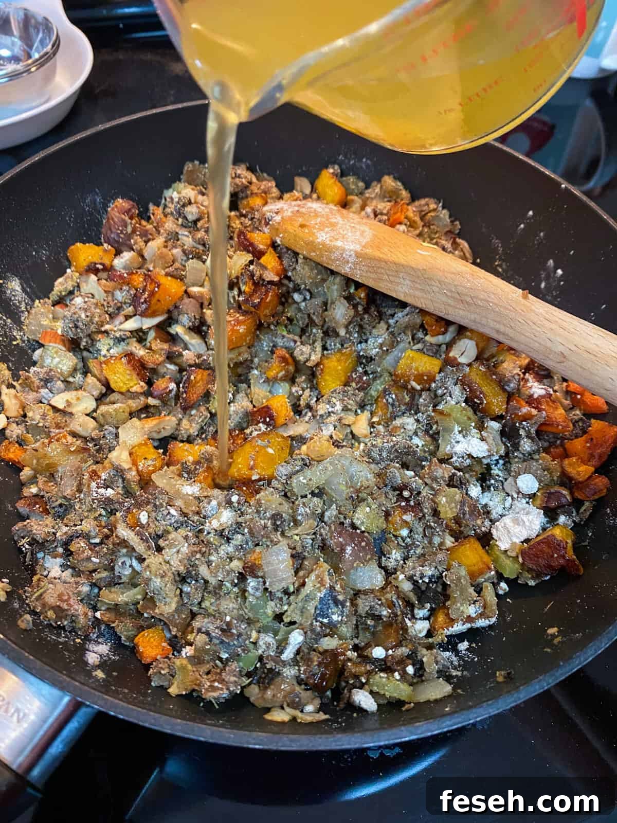 Photo of ingredients in a pan and pouring in stock.
