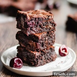 Stack of three cut brownies to expose the cherries inside.