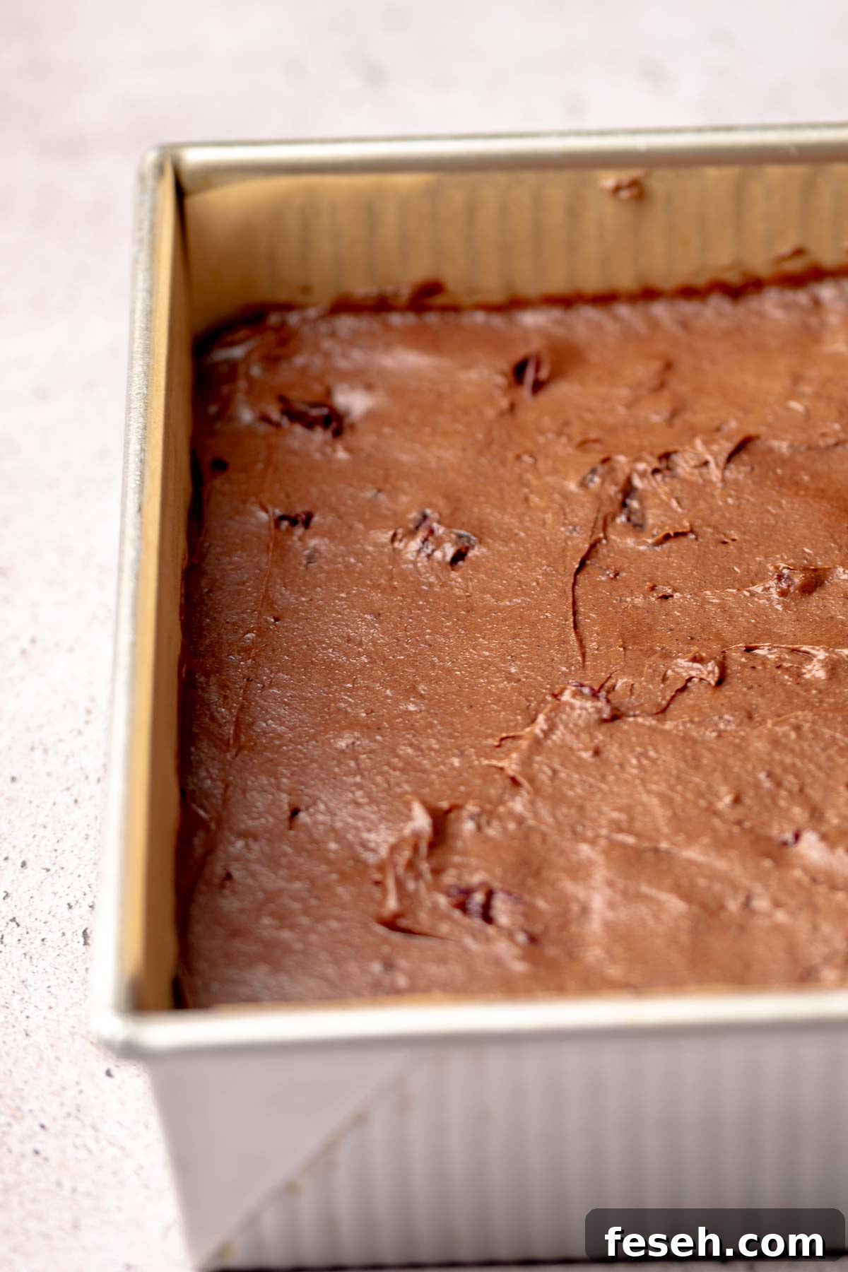 Brownie batter spread into a square pan.