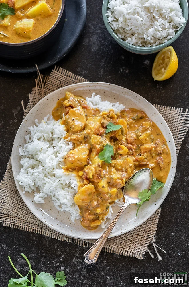 vegan potato curry served with rice in a white plate and garnished with cilantro