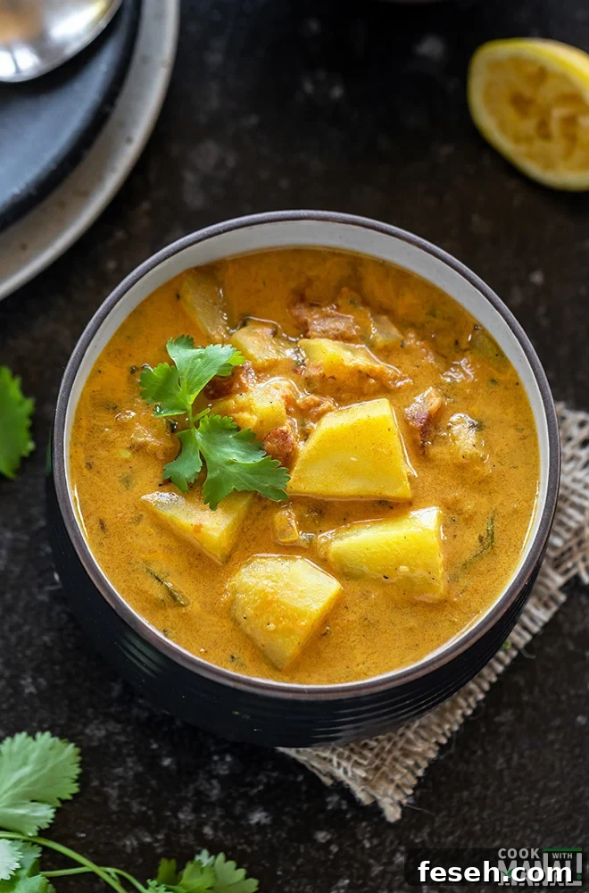 overhead shot of potato curry served in a black bowl and garnished with cilantro