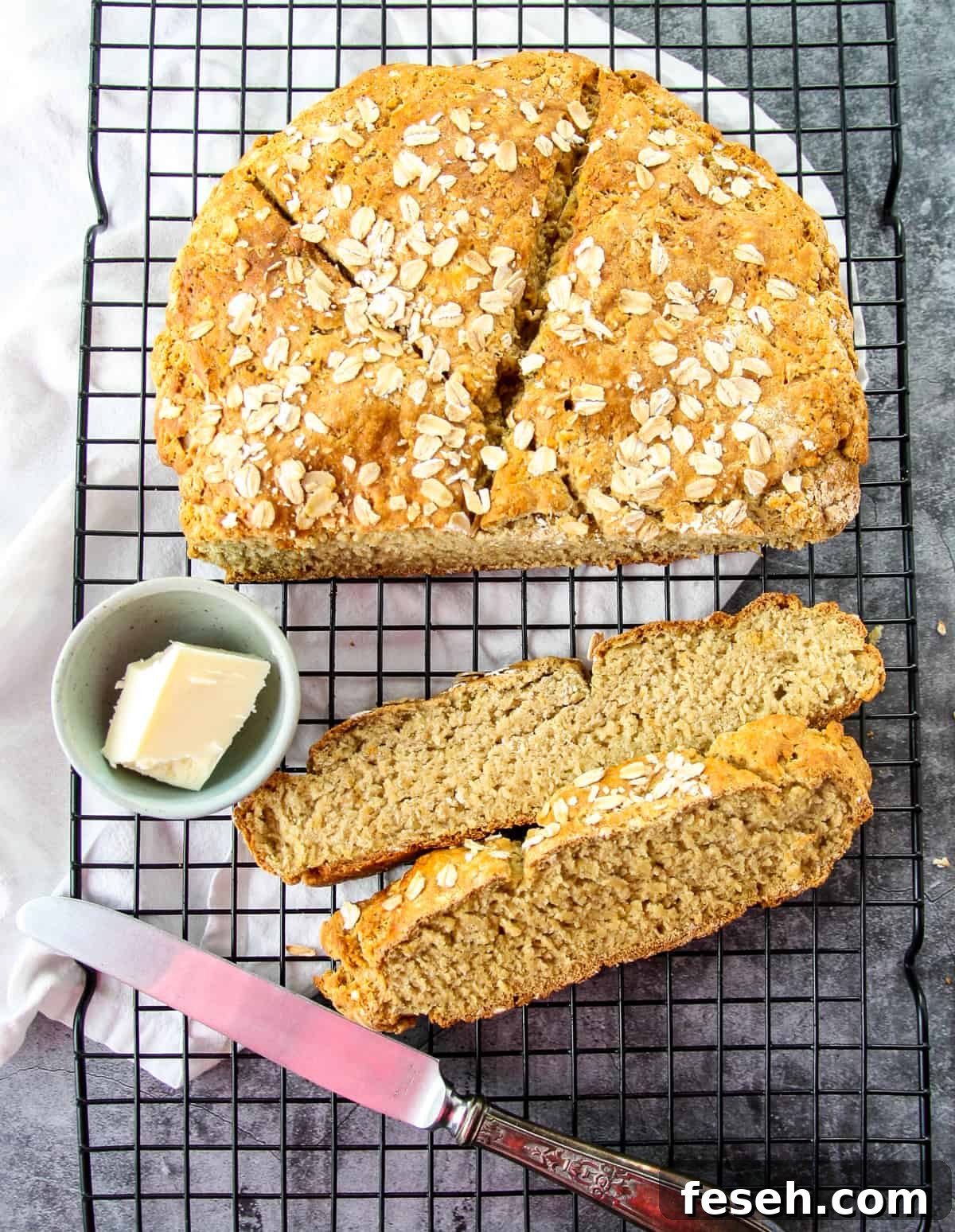 A round loaf of gluten-free Irish soda bread with two slices removed, and a small dish of butter.
