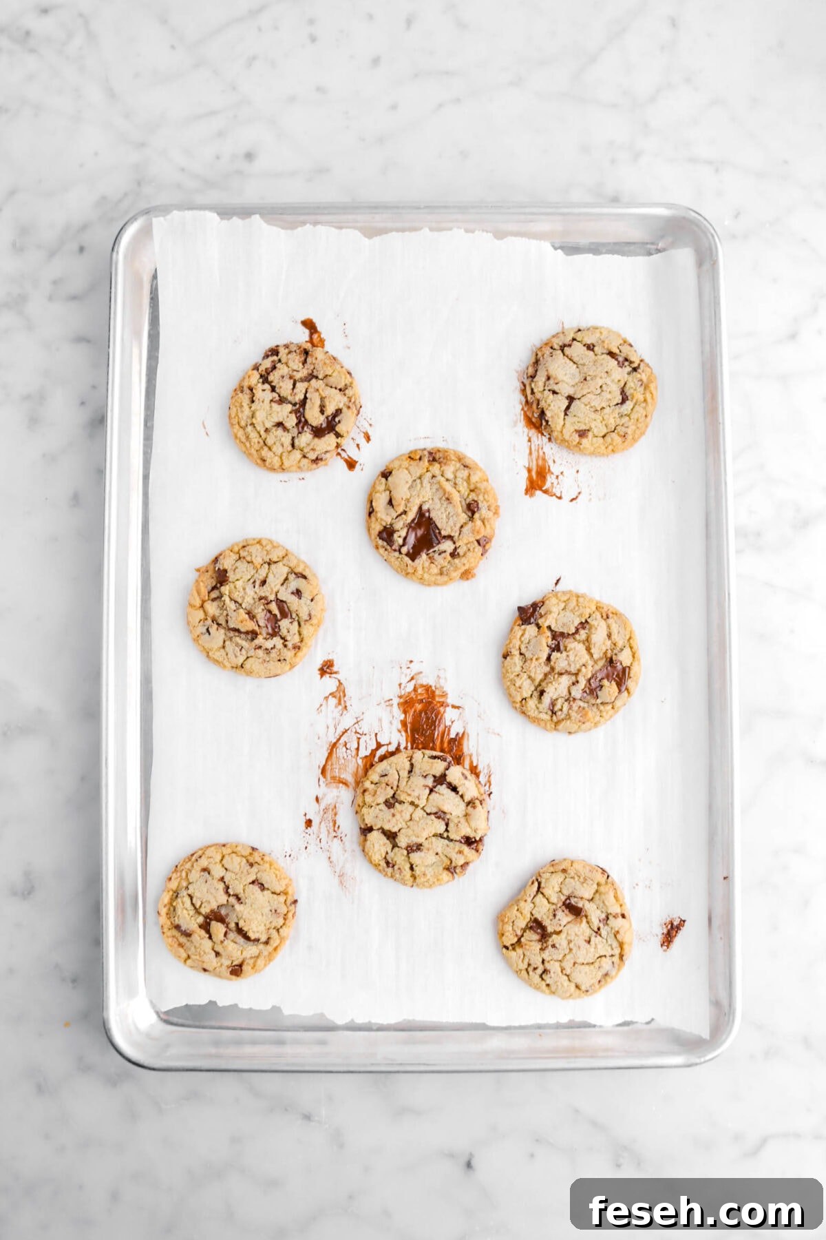 eight chocolate chip cookies on lined sheet pan.