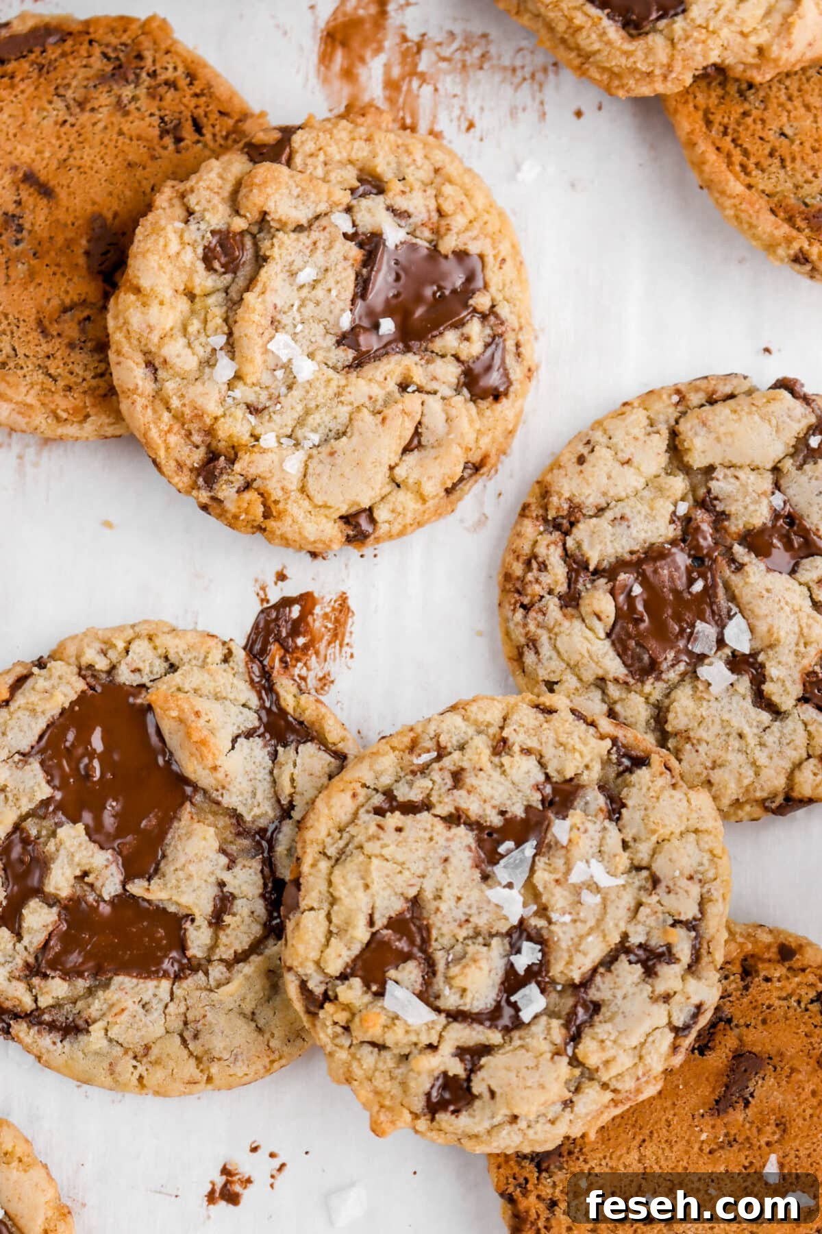 close up overhead shot of four chocolate chip cookies with flaked salt on three of them.
