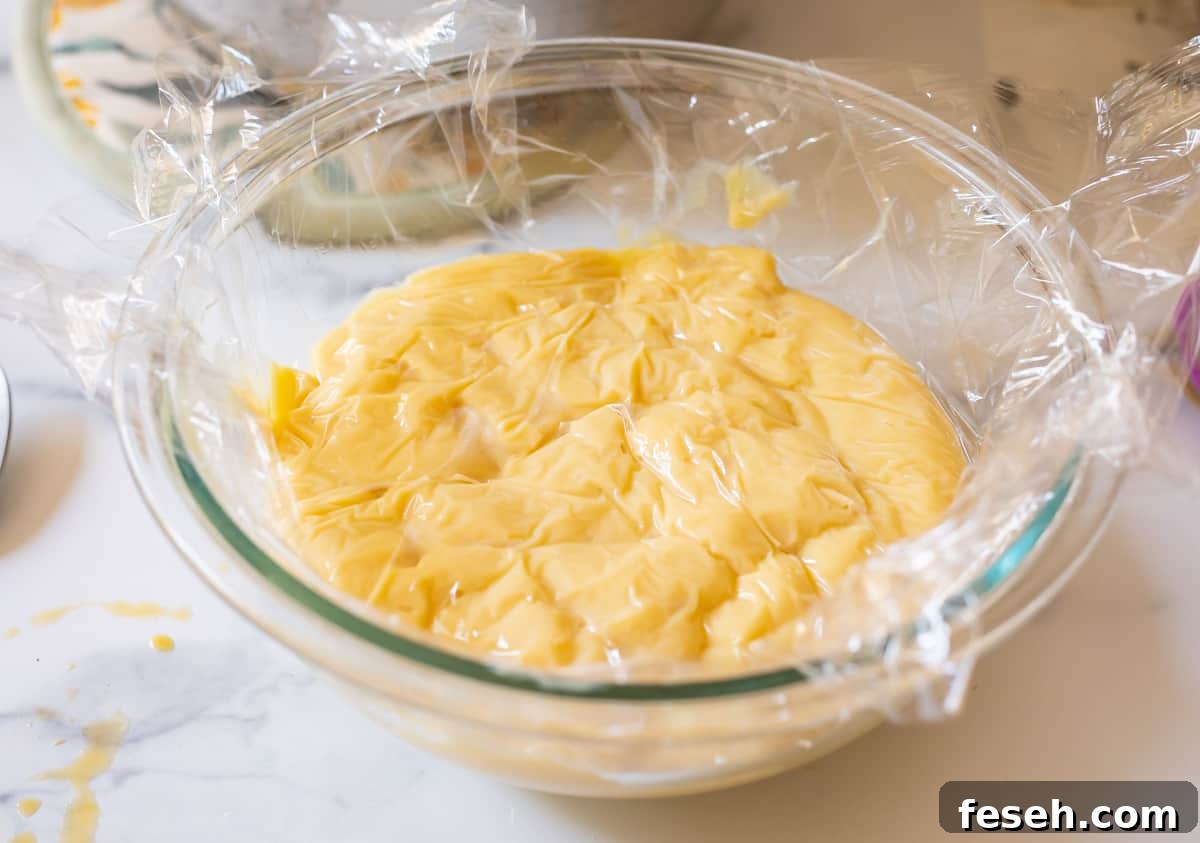 glass bowl filled with Crème Pâtissière with plastic wrap pushed directly on top to prevent film.