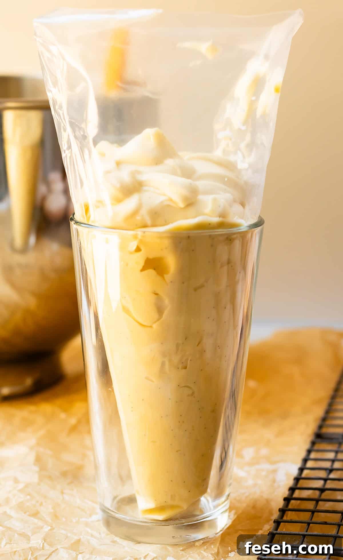 a drinking glass holding up a pastry bag that is filled with homemade pastry cream.