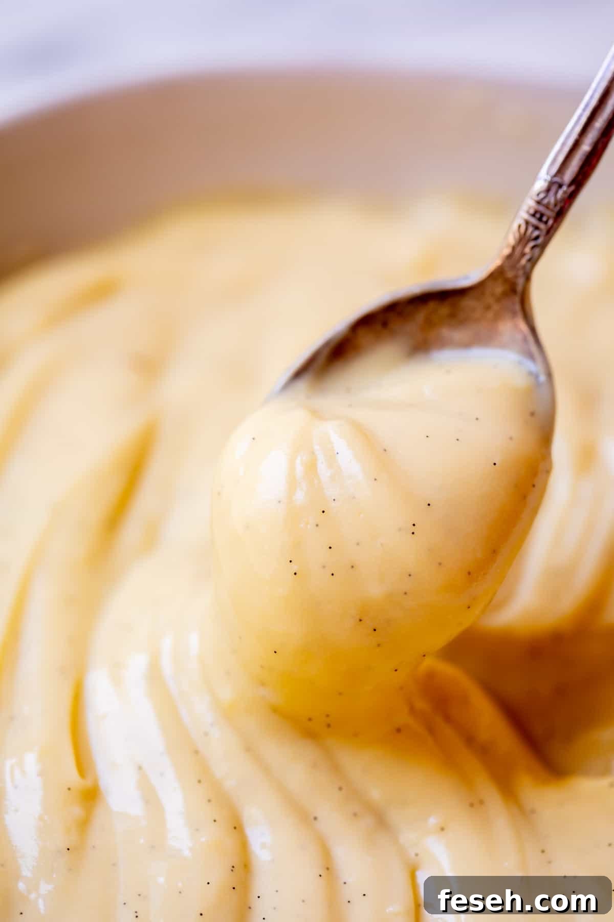 spoon holding up vanilla bean flecked Crème Pâtissière ready to be eaten.