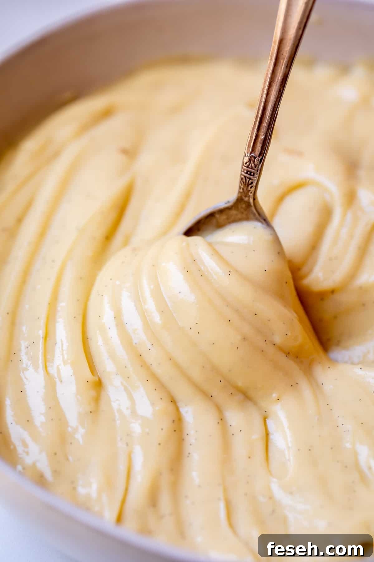 spoon lifting up as if to pour out pastry cream, but the cream is thick and sticks to the spoon.