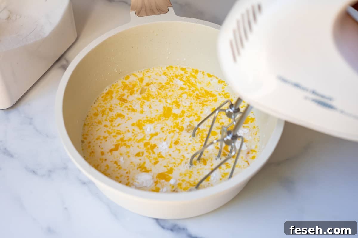 egg, sugars, and milk being mixed by a handmixer in order to make homemade pastry cream.
