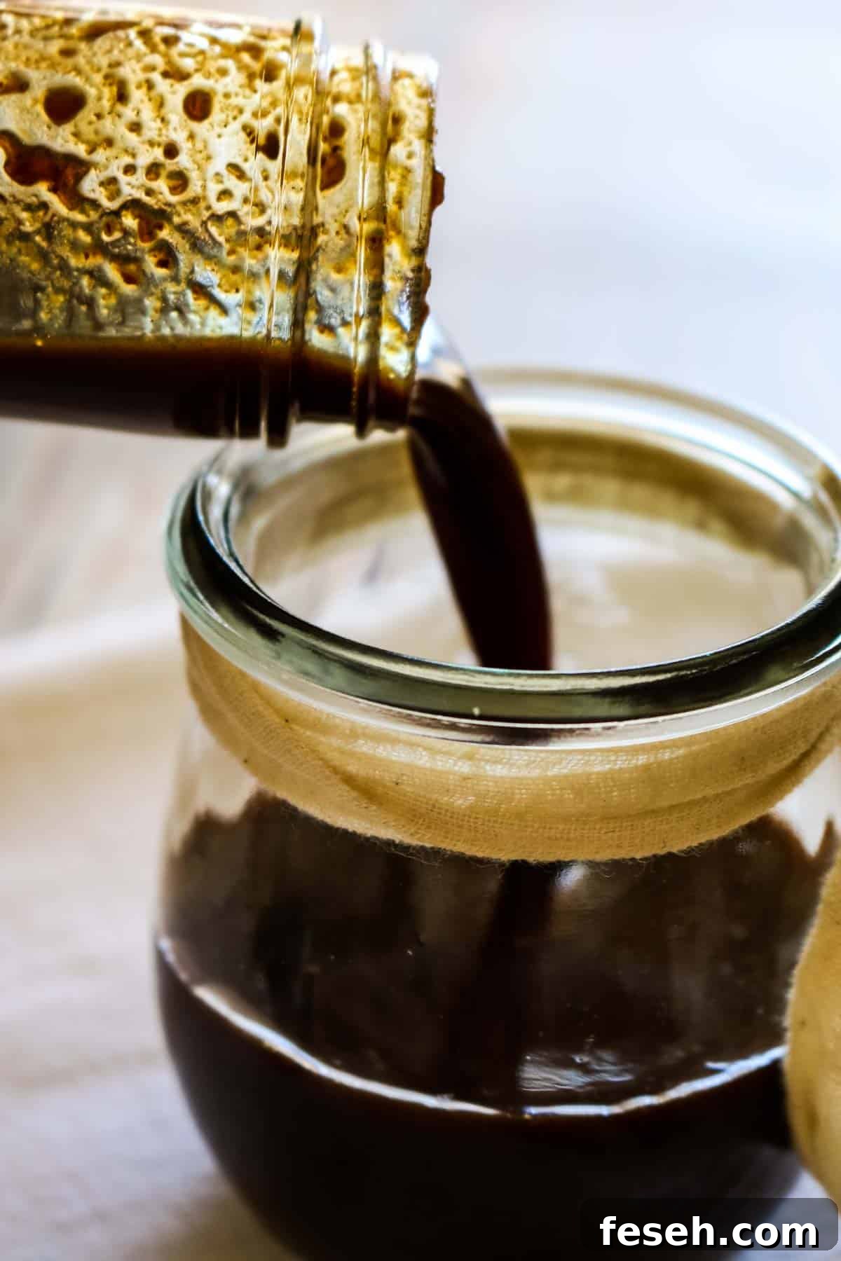 dark sauce being poured into a jar.