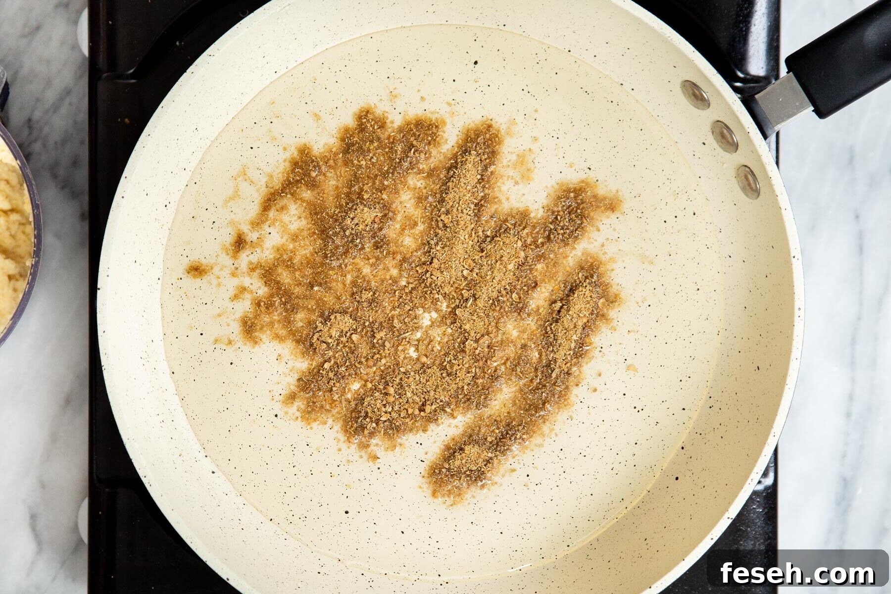 ground spices frying in a saucepan with oil 