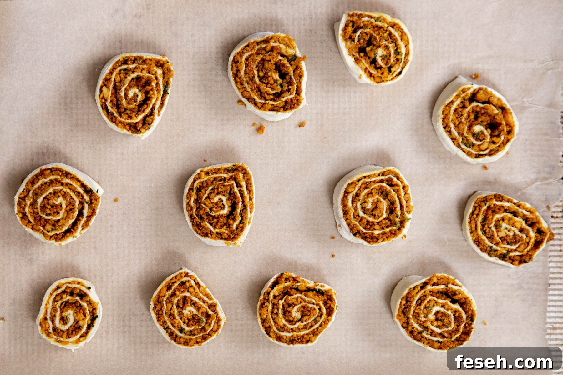 vegan pinwheels on a sheet of parchment paper ready for baking 