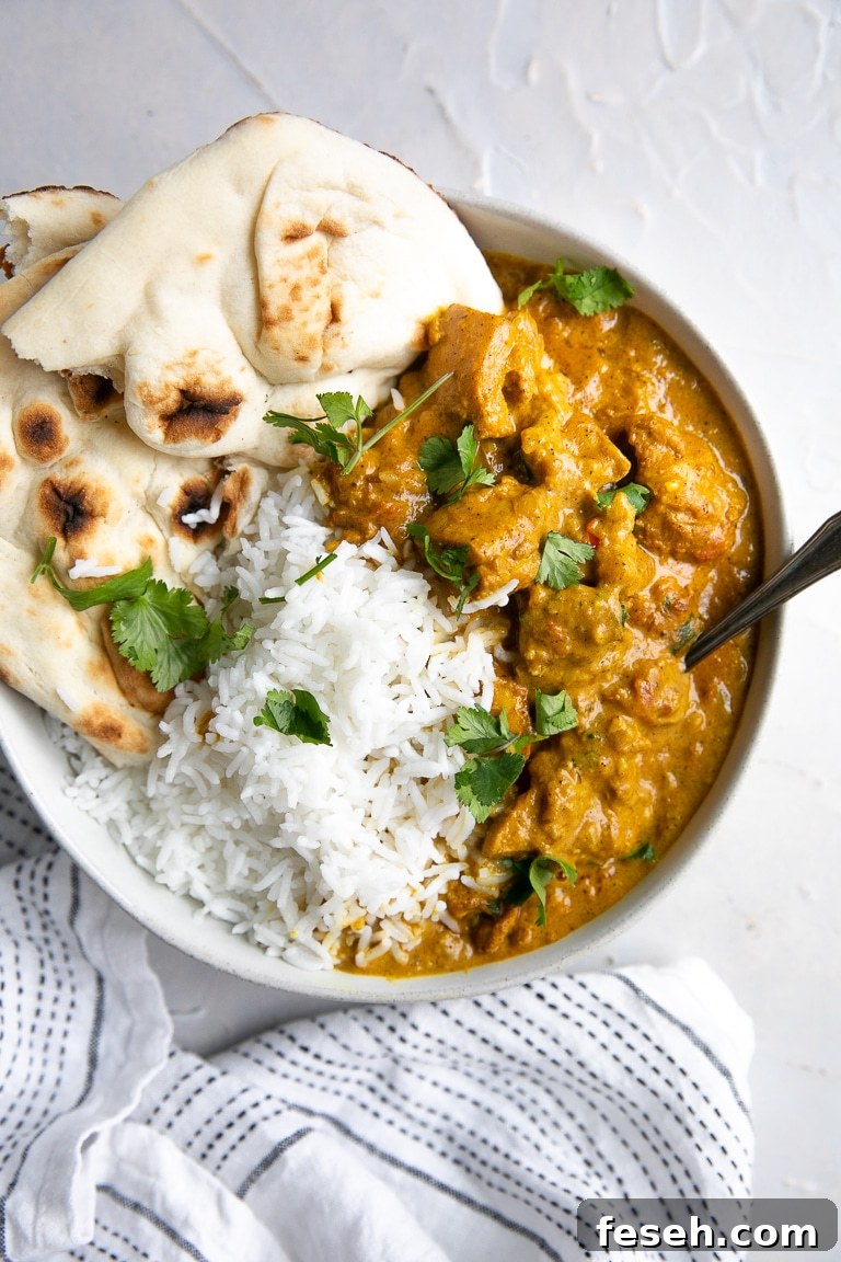 Shallow white bowl filled with creamy butter chicken and rice.
