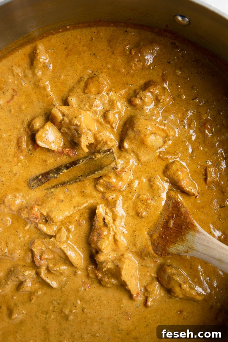 Close-up image of butter chicken simmering in a large pot.