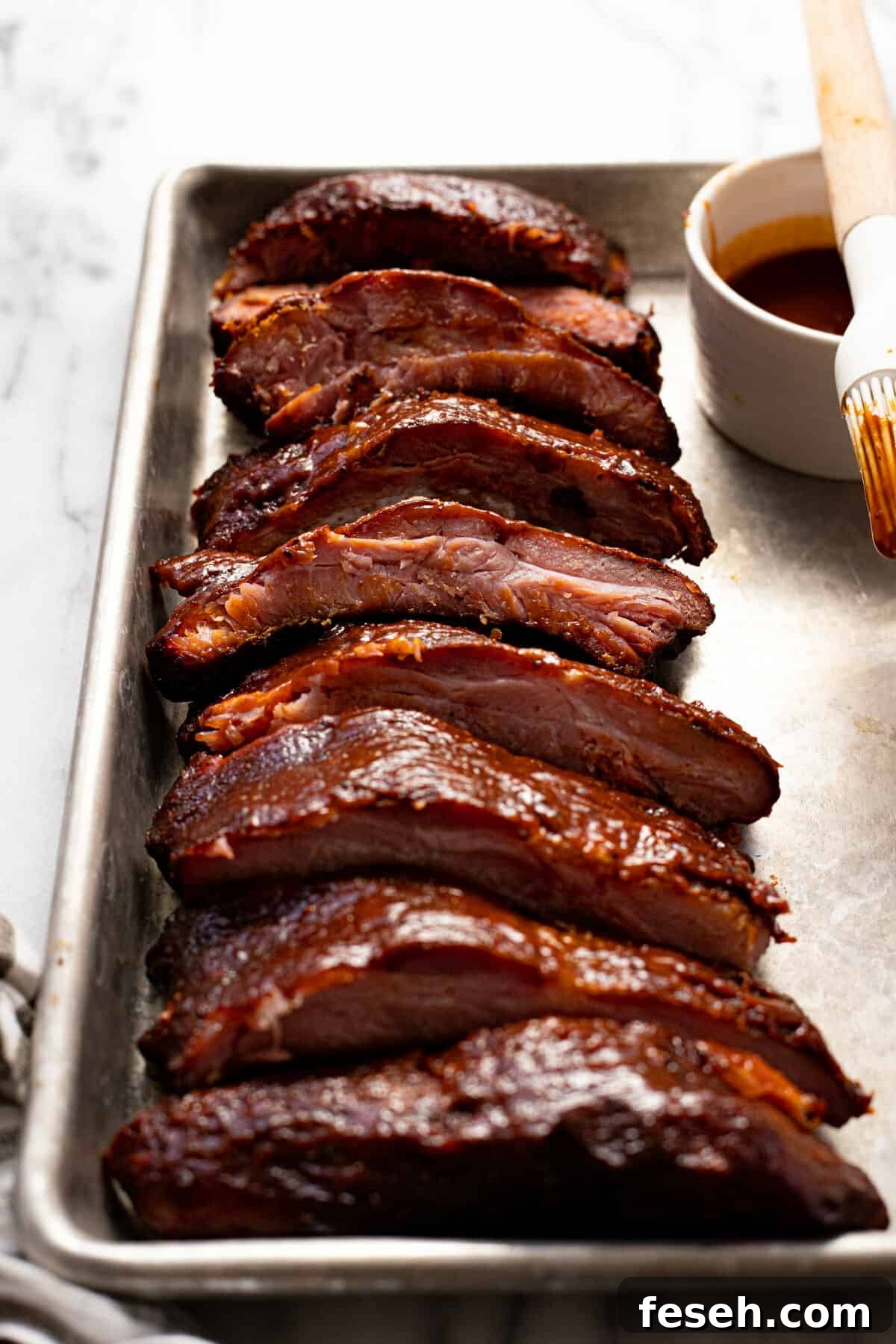Close up shot of sliced baby back ribs on a baking sheet.