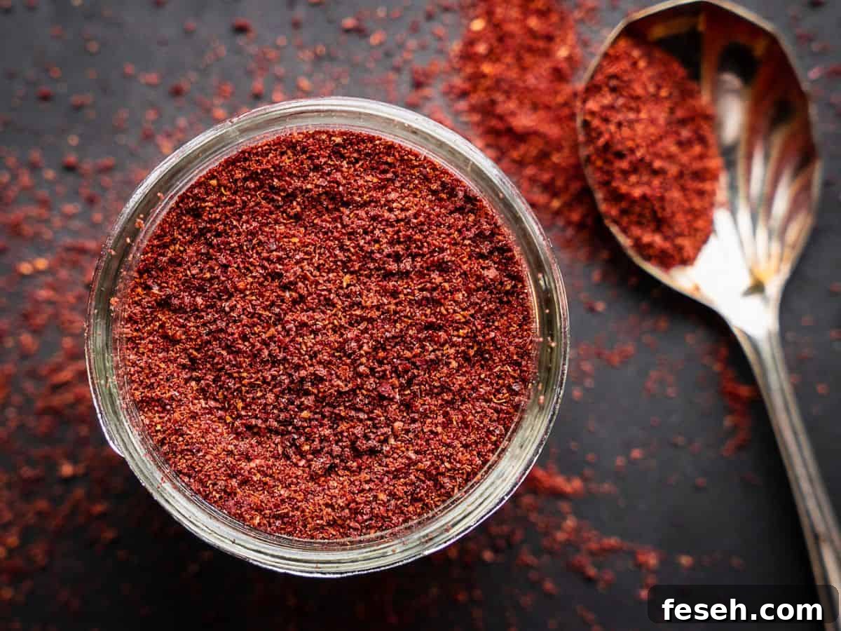 Sumac spice with spoon in an open mason jar.