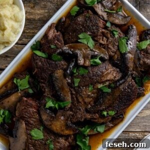 Cooked sliced roast topped with mushrooms and sliced portobella mushrooms on a white serving platter.