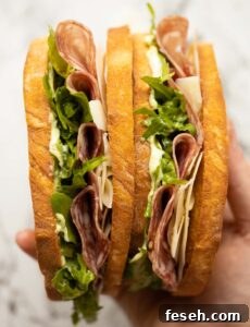 close up overhead shot of hand holding two salami sandwiches
