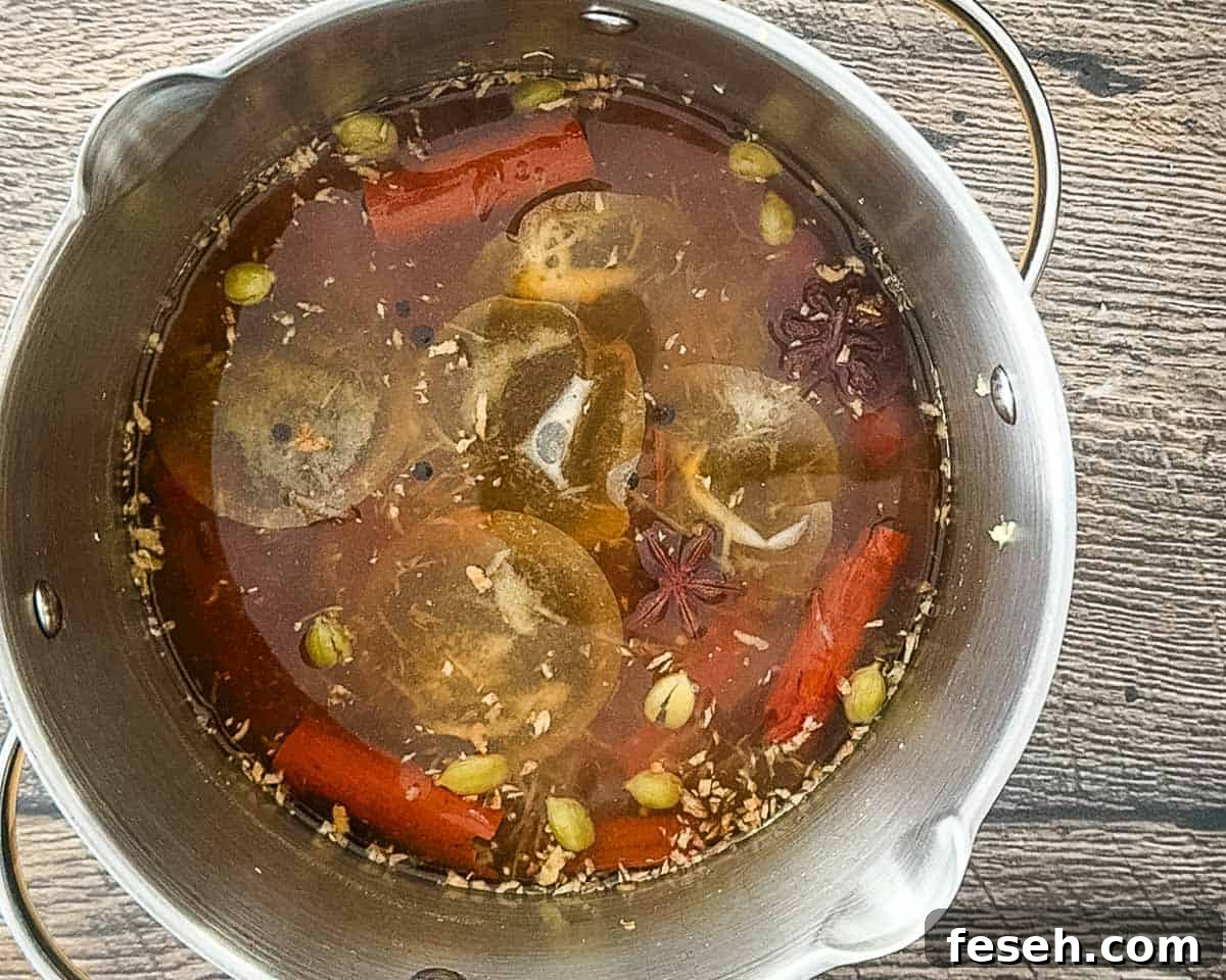 Tea bags steeping in spiced liquid in a saucepan after simmering.