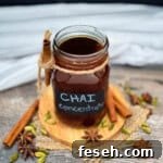 Homemade chai tea concentrate in a mason jar with cinnamon sticks, cardamom, and whole spices.