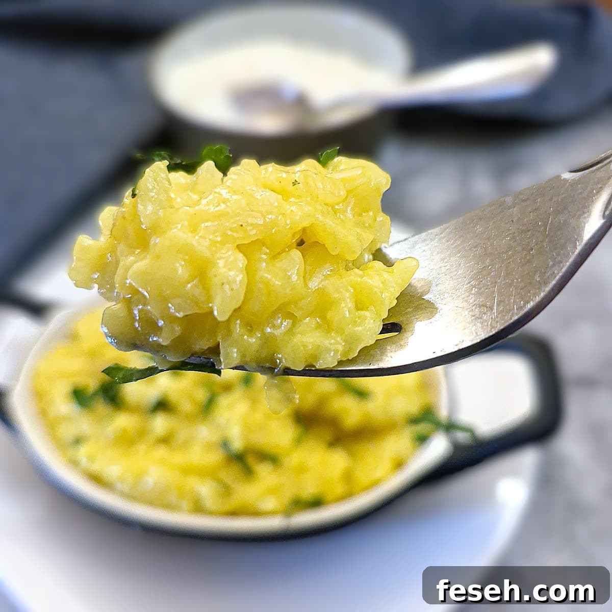 A forkful of risotto alla Milanese being lifted from a serving dish.