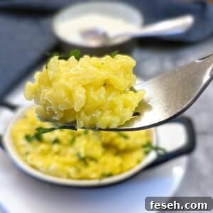 A forkful of risotto alla Milanese being lifted from a serving dish.
