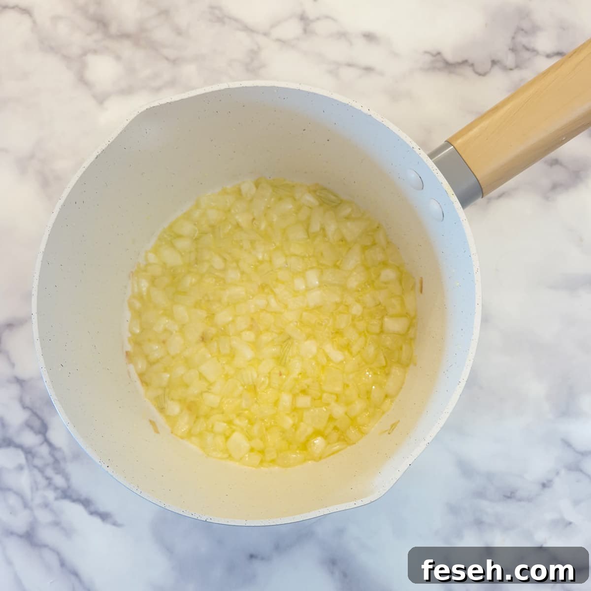Onions softening in butter and olive oil in a saucepan.