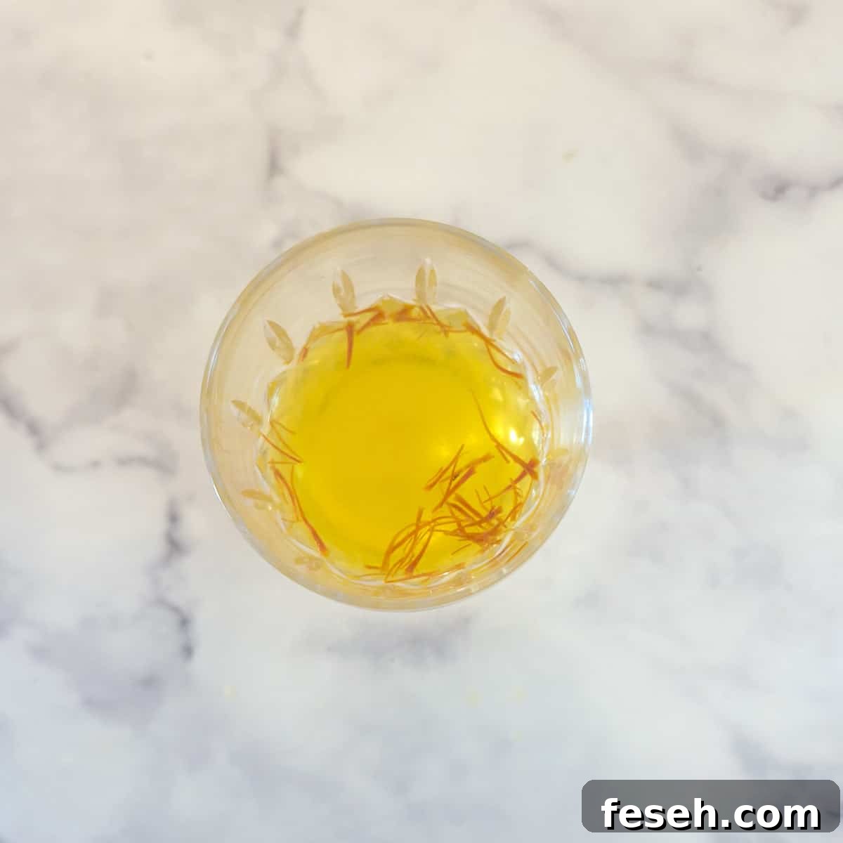 Saffron threads soaking in a mixture of vinegar and vinegar in a wine glass.