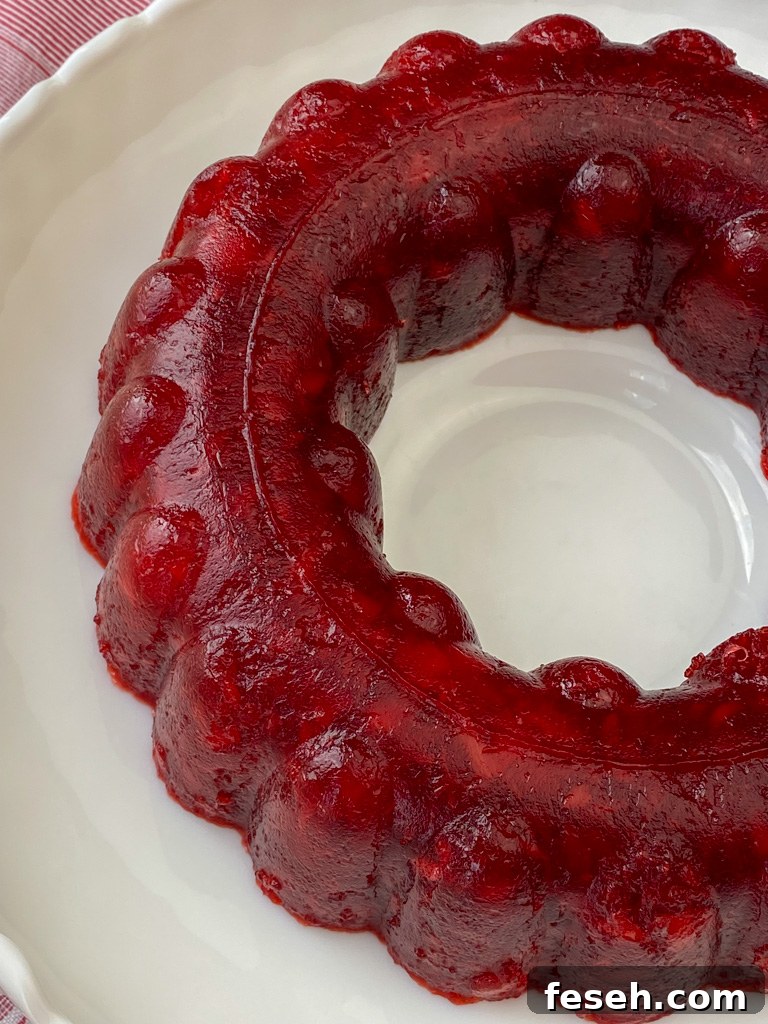 Cherry Coke Jello Salad Recipe — Retro Fizzy Dessert 3 Overhead view of a ring of red jello salad with cherry pie filling, cherry coke and black cherry jello on a white serving platter.