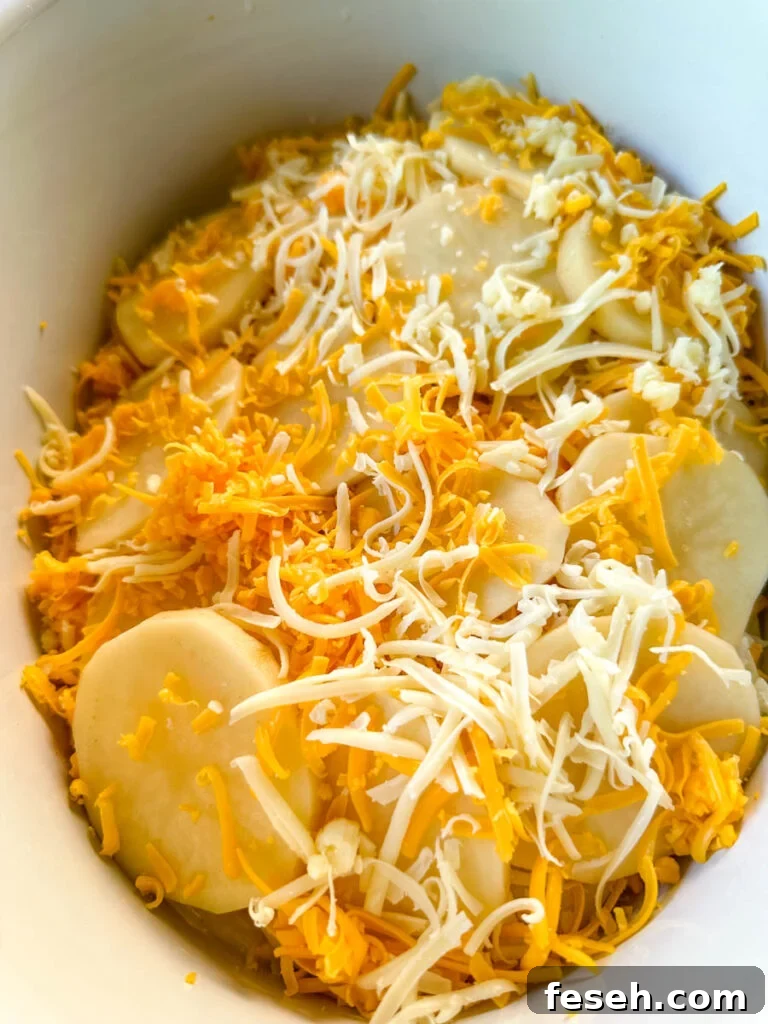 uncooked slow cooker cheesy potatoes in a white Crockpot
