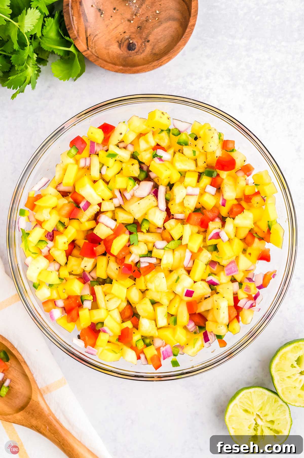 bowl of pineapple salsa with squeezed limes next to it