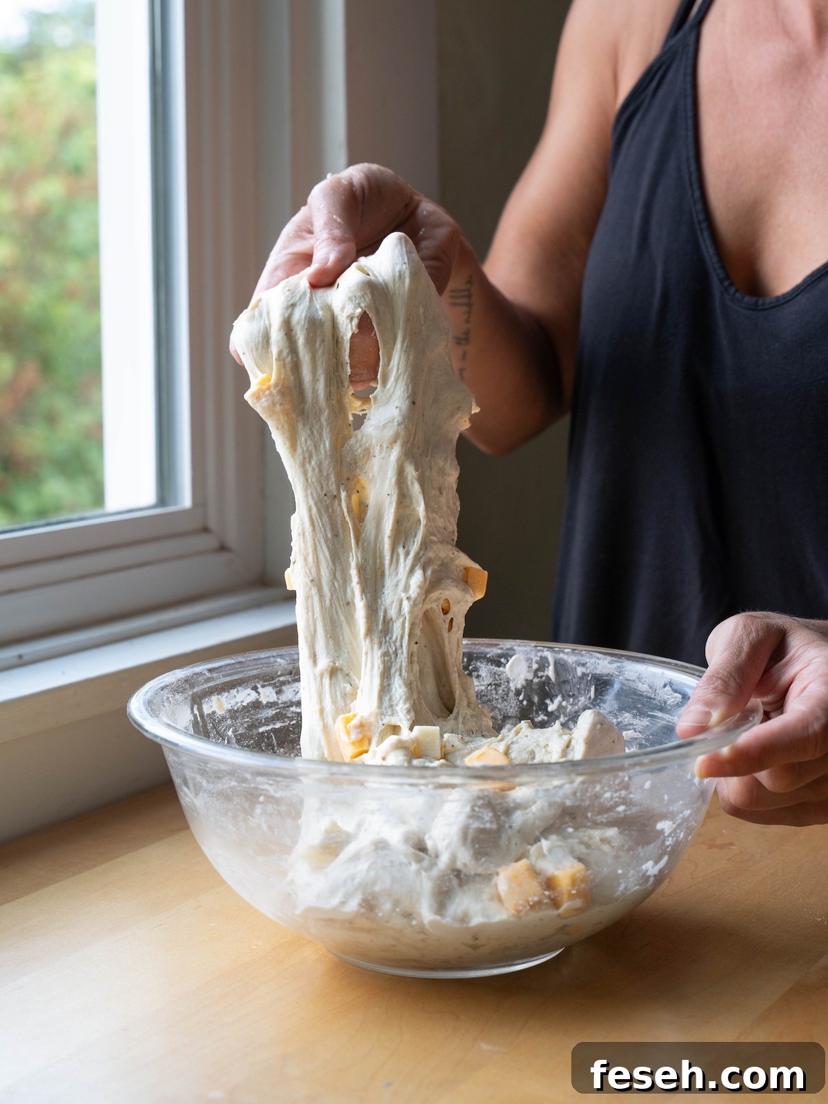 Stretching cheesy sourdough bread dough to build gluten