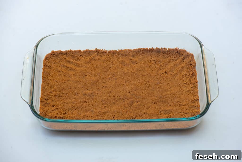 A gingersnap crust spread across the bottom of a glass baking dish.