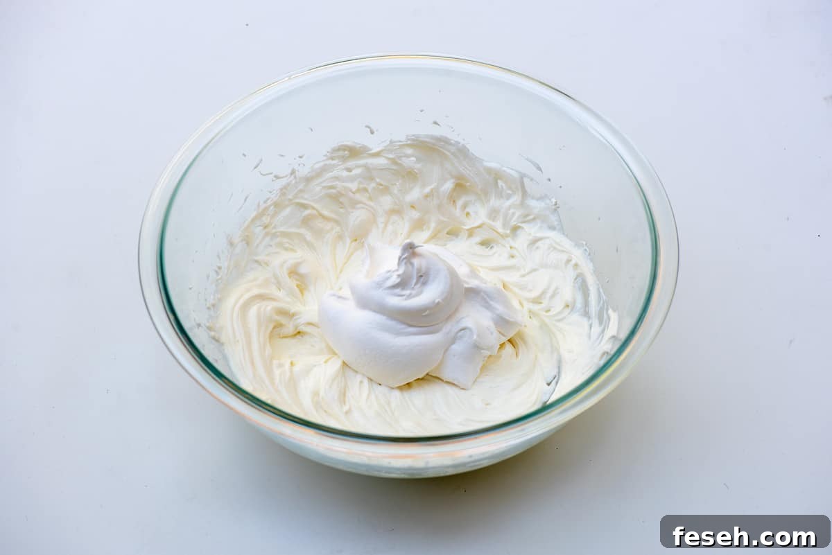 Pudding and whipped topping in a glass mixing bowl.