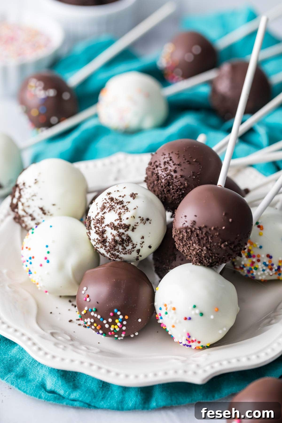 Cake pops coated in white and dark chocolate on a plate.