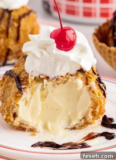 Deep fried ice cream with a bite taken out on a plate topped with whipped cream and a cherry.