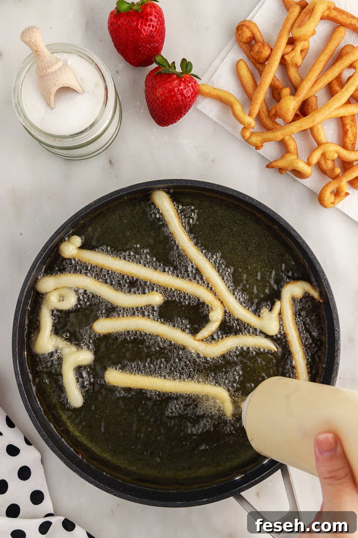 Funnel Cake Fries batter squeezed into a pan of oil.