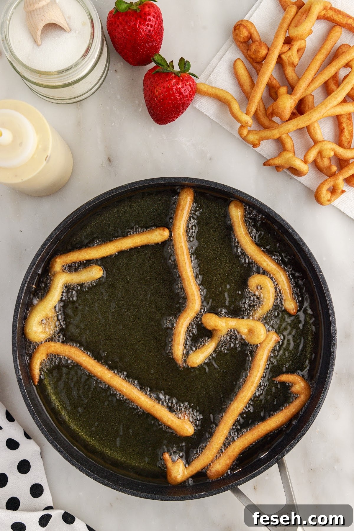 Funnel Cake Fries in a pan of oil.