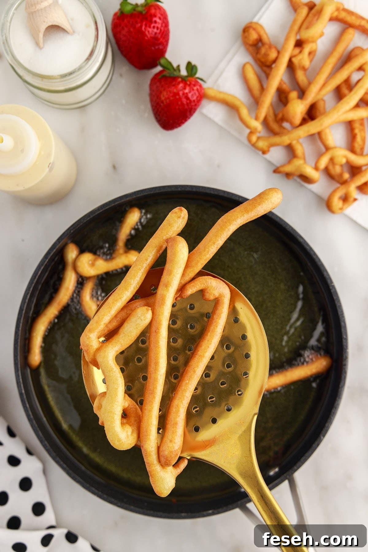 A slotted spoon lifting out Funnel Cake Fries.