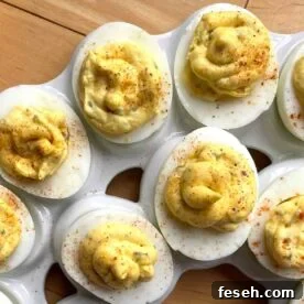 Two rows of cajun deviled eggs on a white platter.
