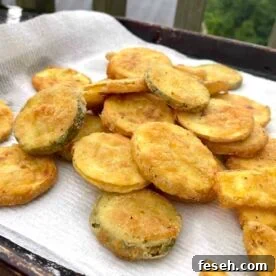 Fried squash slices draining on a paper towel.