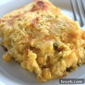 A slice of corn pudding with cheese and jalapeños on a white plate.
