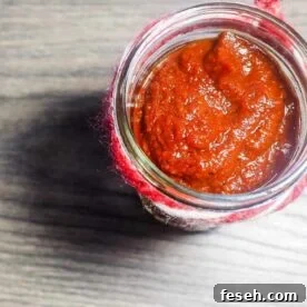 A jar of barbecue sauce with a ribbon around the top on a gray wooden background.