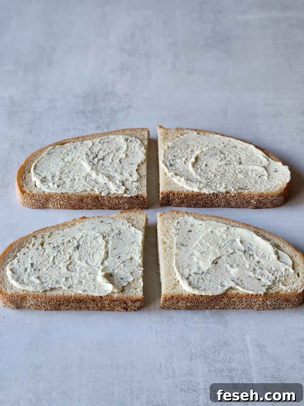 Four slices of bread with Boursin cheese spread on the top.