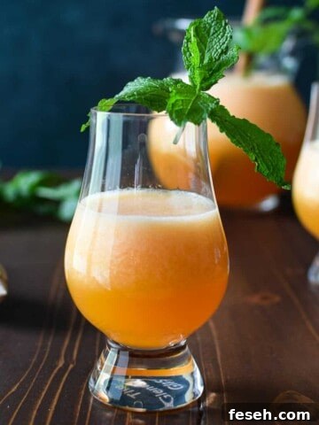 Eye level view of canteloupe lime agua fresca on a wooden background with mint in the glass