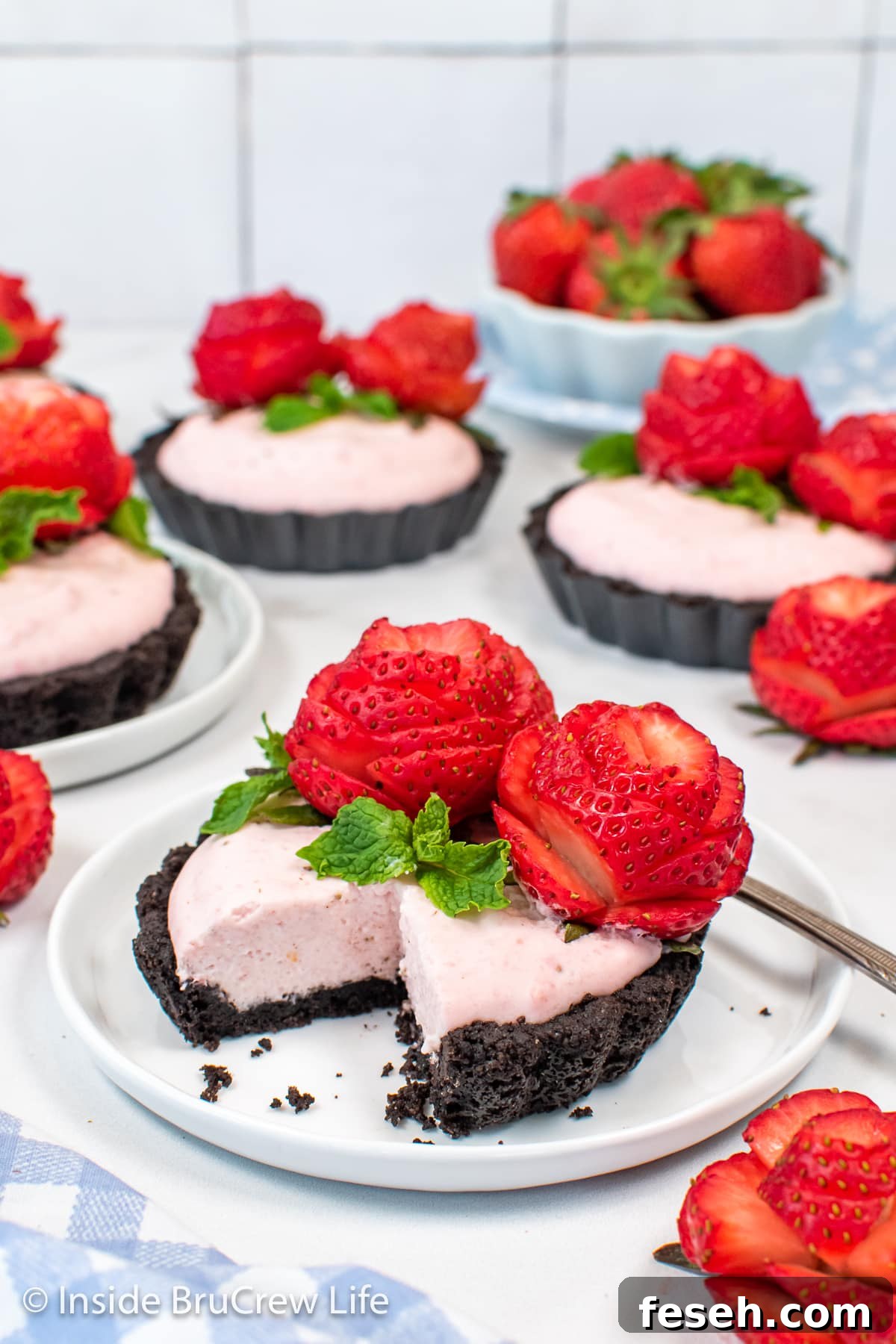A pink strawberry tart with Oreo crust on white plates.
