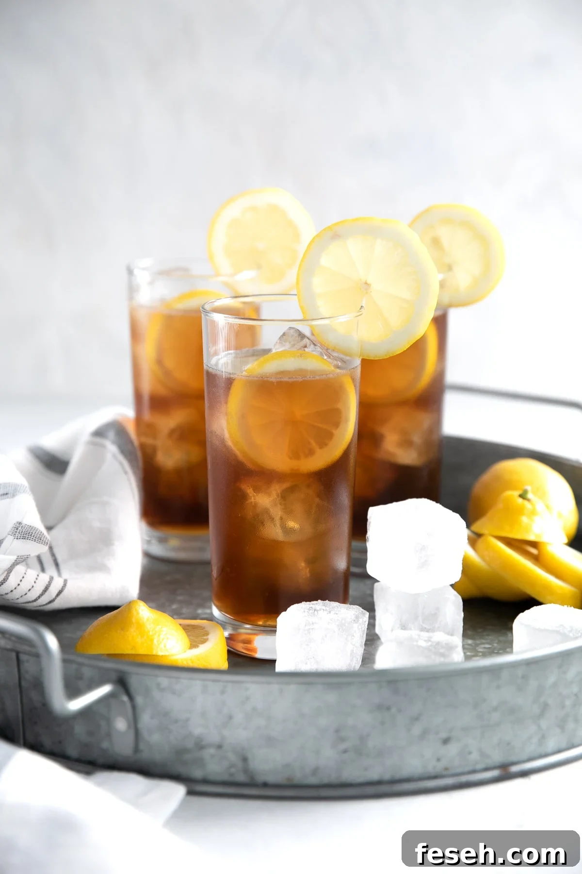 Three ice-cold Long Island Iced Tea on a large metal serving tray.