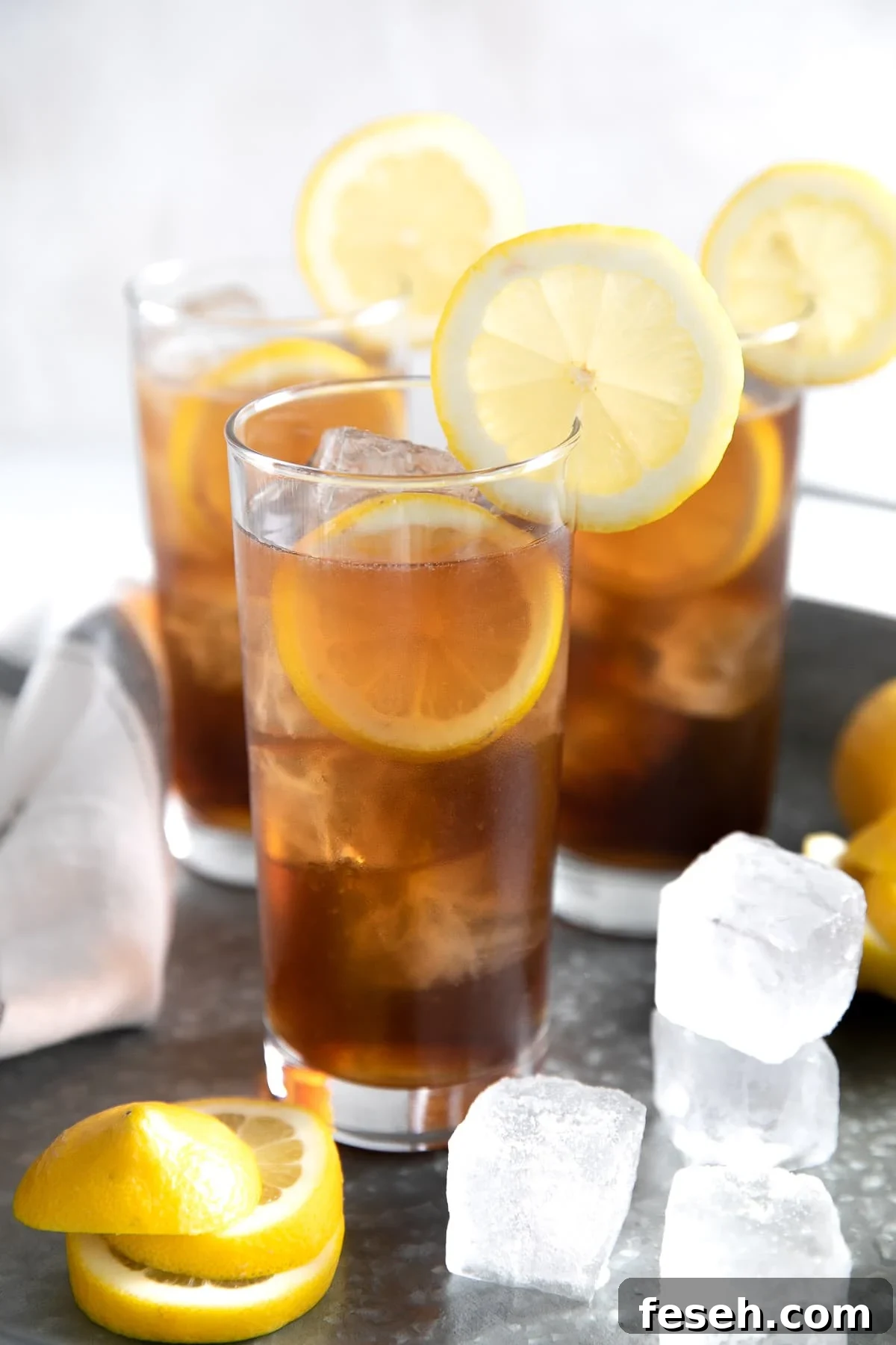 Three ice-cold Long Island Iced Tea on a large metal serving tray.